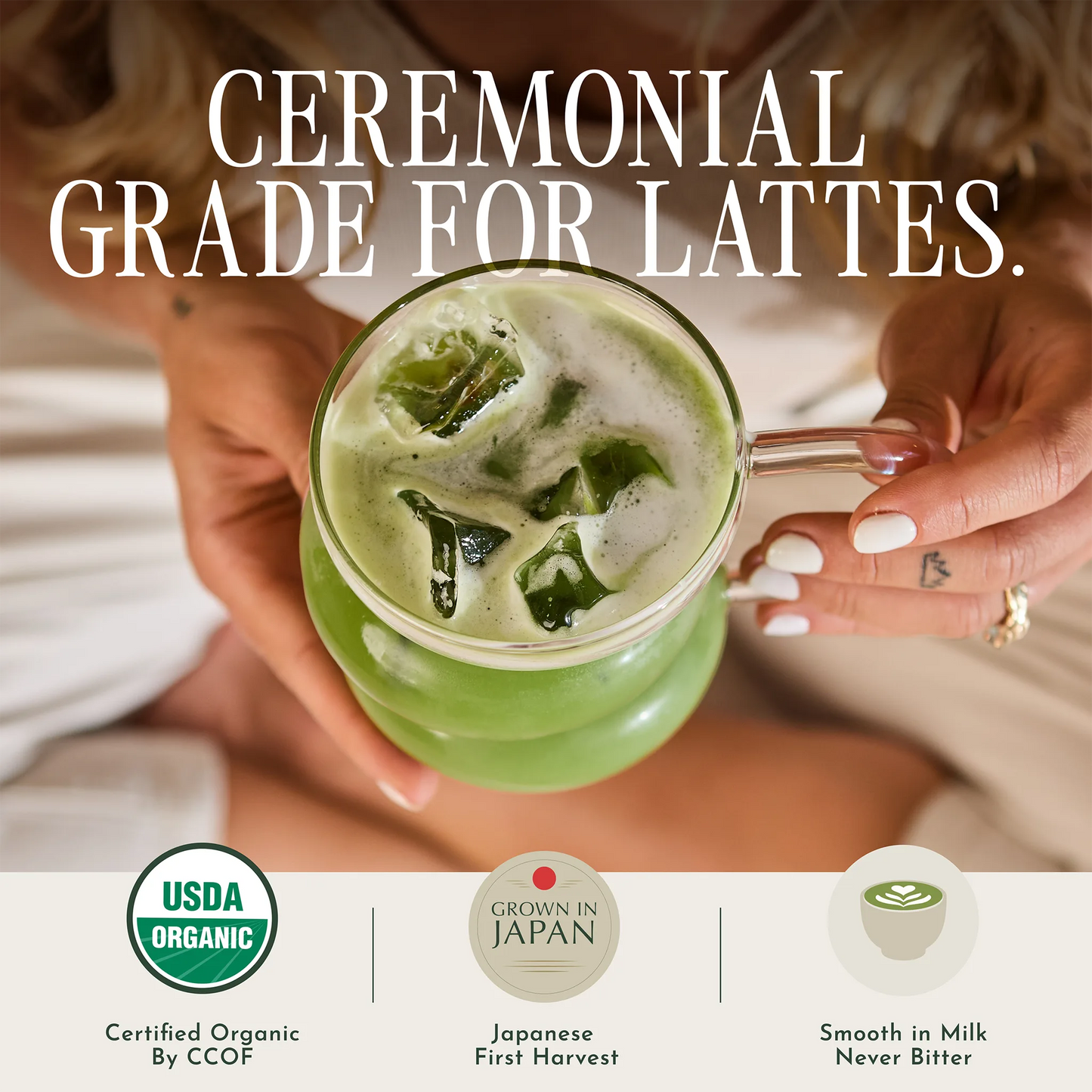 Person holding a green iced latte with text about ceremonial grade for lattes and certification logos.