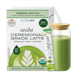 A box of Encha Ceremonial Grade Latte organic matcha single-serve sticks next to a glass jar filled with green matcha latte and a bamboo lid with a clear straw, on a white background. _Single serve sticks 30 pack