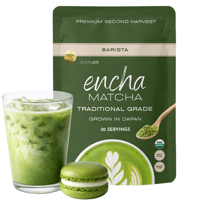 A pouch of Encha Matcha Traditional Grade matcha powder stands behind a glass of green iced matcha latte and a green matcha macaron, on a clean white background. _60g (2.12 oz) 30 cups