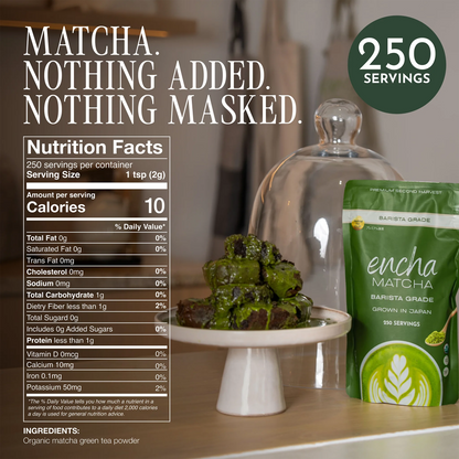 A green pouch of Encha Matcha Barista Grade matcha green tea powder is shown next to a glass cloche holding green tea-dusted desserts on a white pedestal, with a Nutrition Facts label and a dark green '250 Servings' badge overlaid on a warm indoor background. __500g (17.64oz) 250 cups